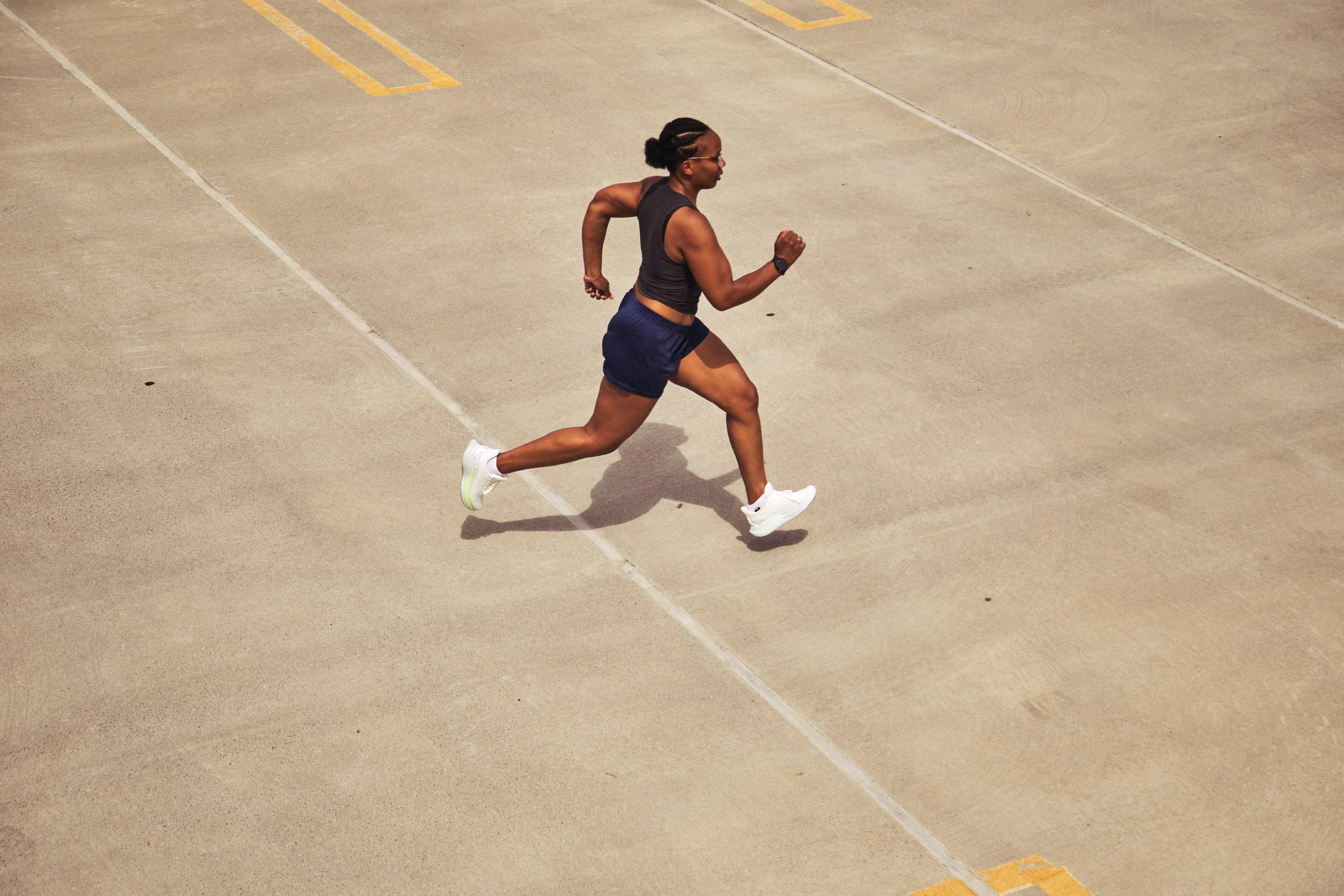 Person running on a concrete surface in athletic gear and white sneakers Person running on a concrete surface in athletic gear and white sneakers