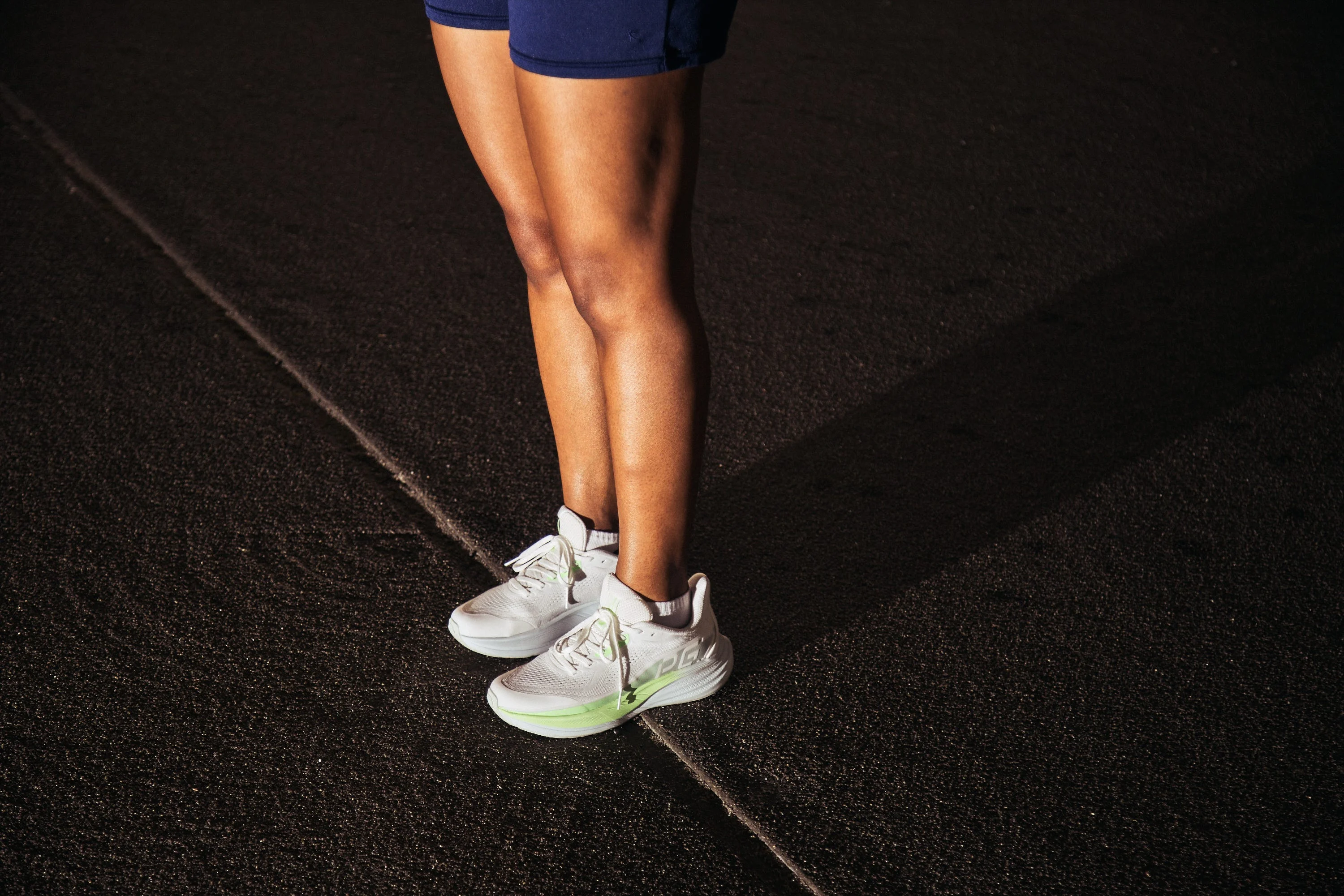 Person standing in athletic shoes on a dark road at night Person standing in athletic shoes on a dark road at night