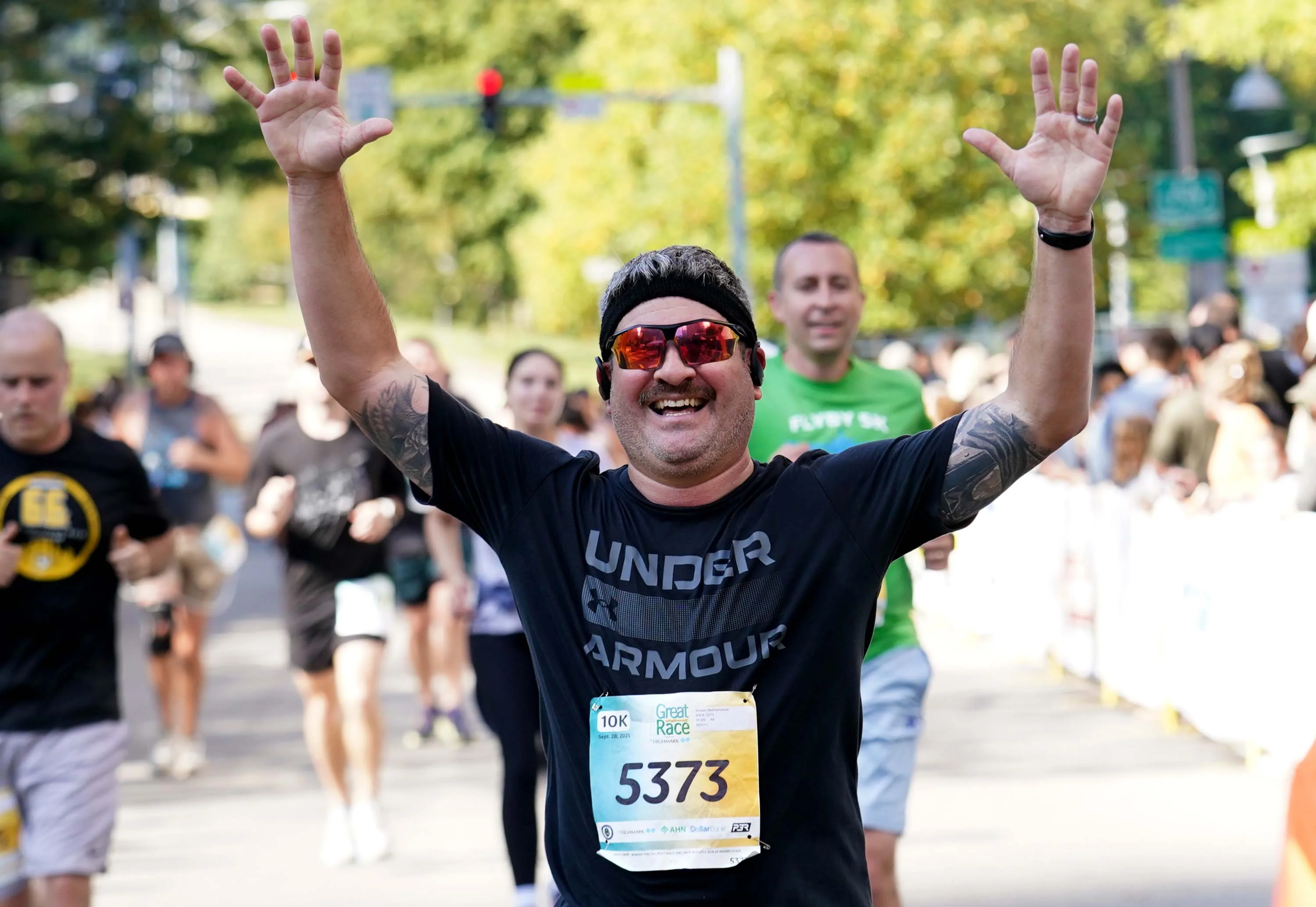 Runner smiling and raising hands at race finish line with crowd in background. Runner smiling and raising hands at race finish line with crowd in background.