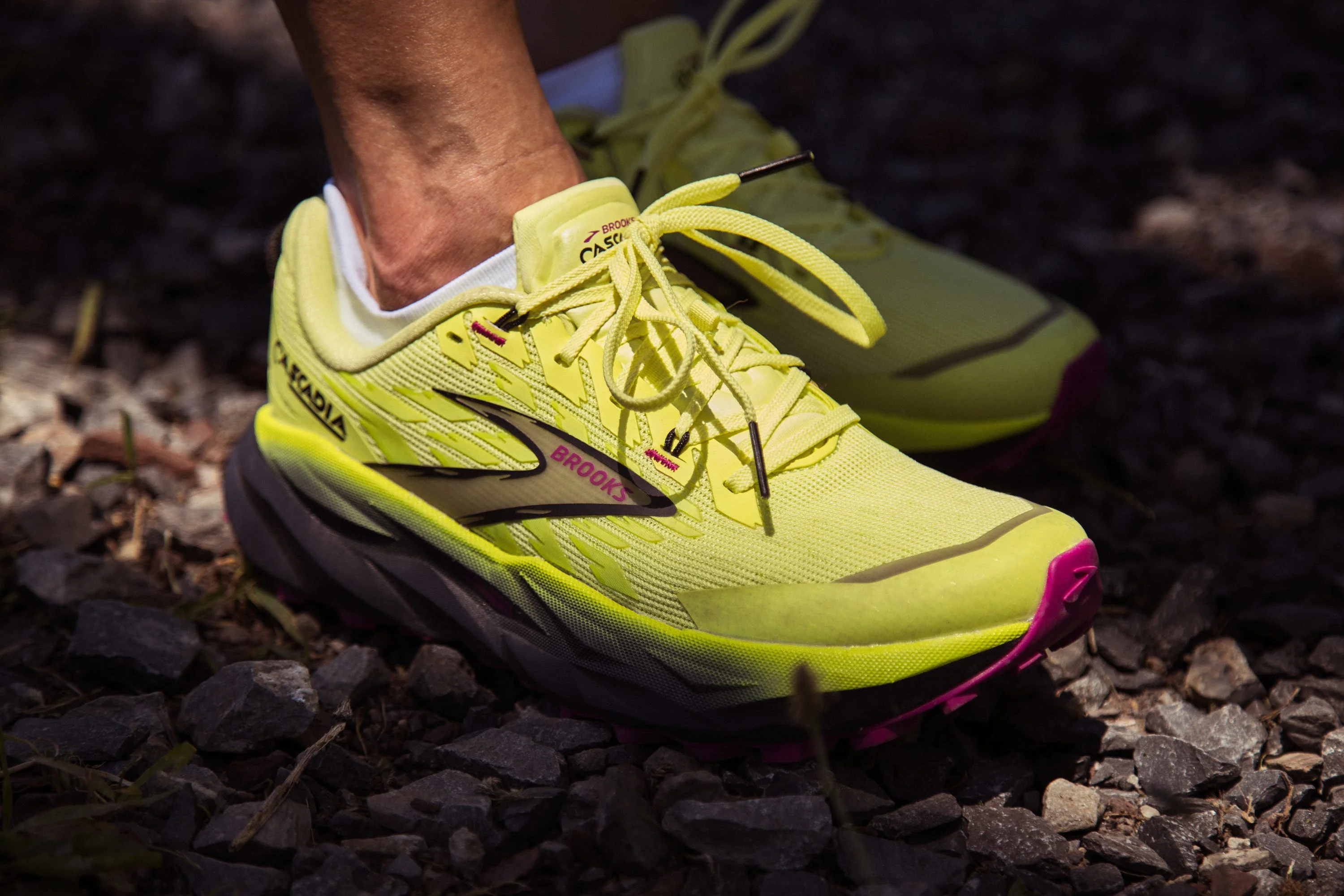 Yellow running shoes with pink accents on gravel. Yellow running shoes with pink accents on gravel.