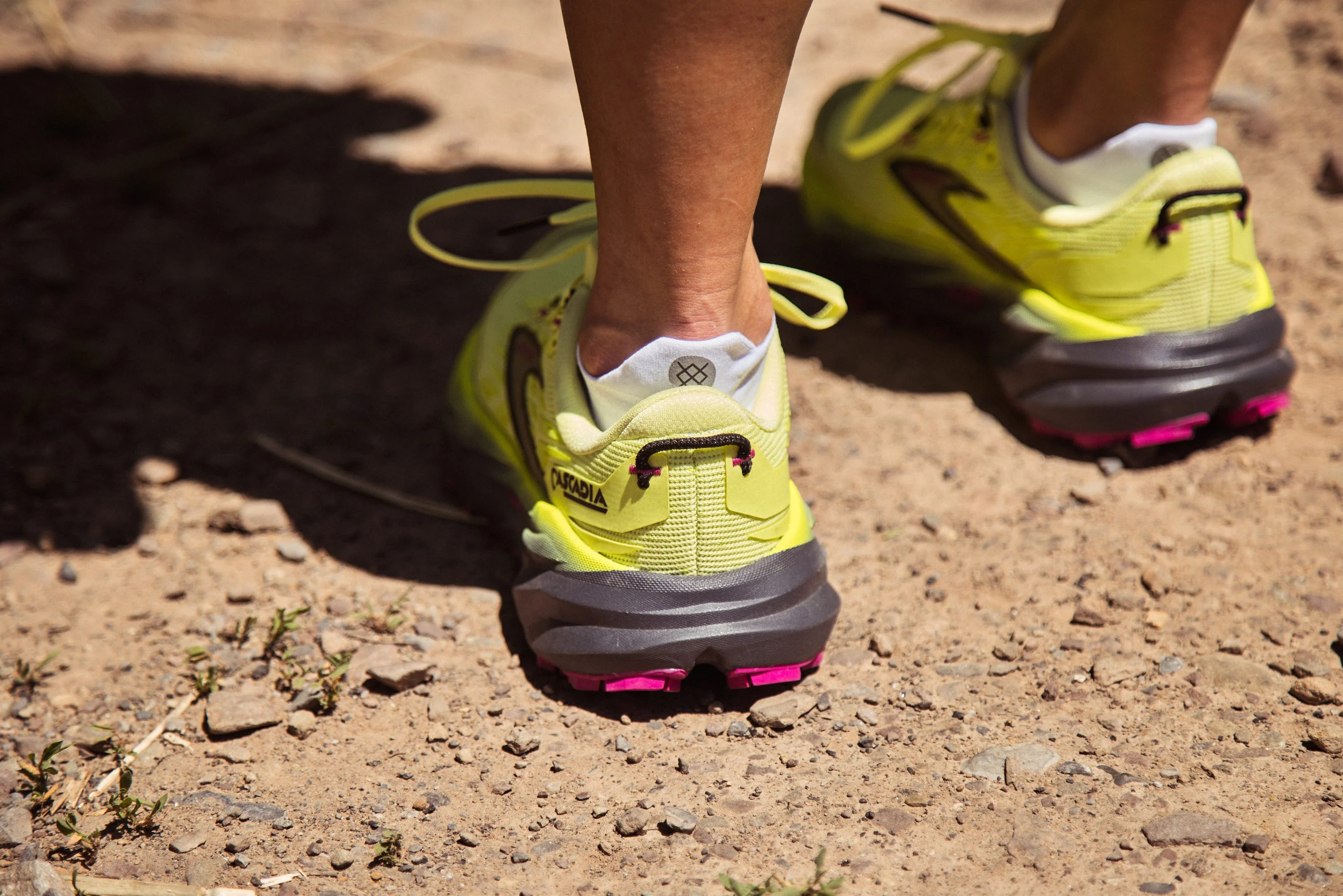 Runner wearing neon yellow trail shoes on a rocky path. Runner wearing neon yellow trail shoes on a rocky path.