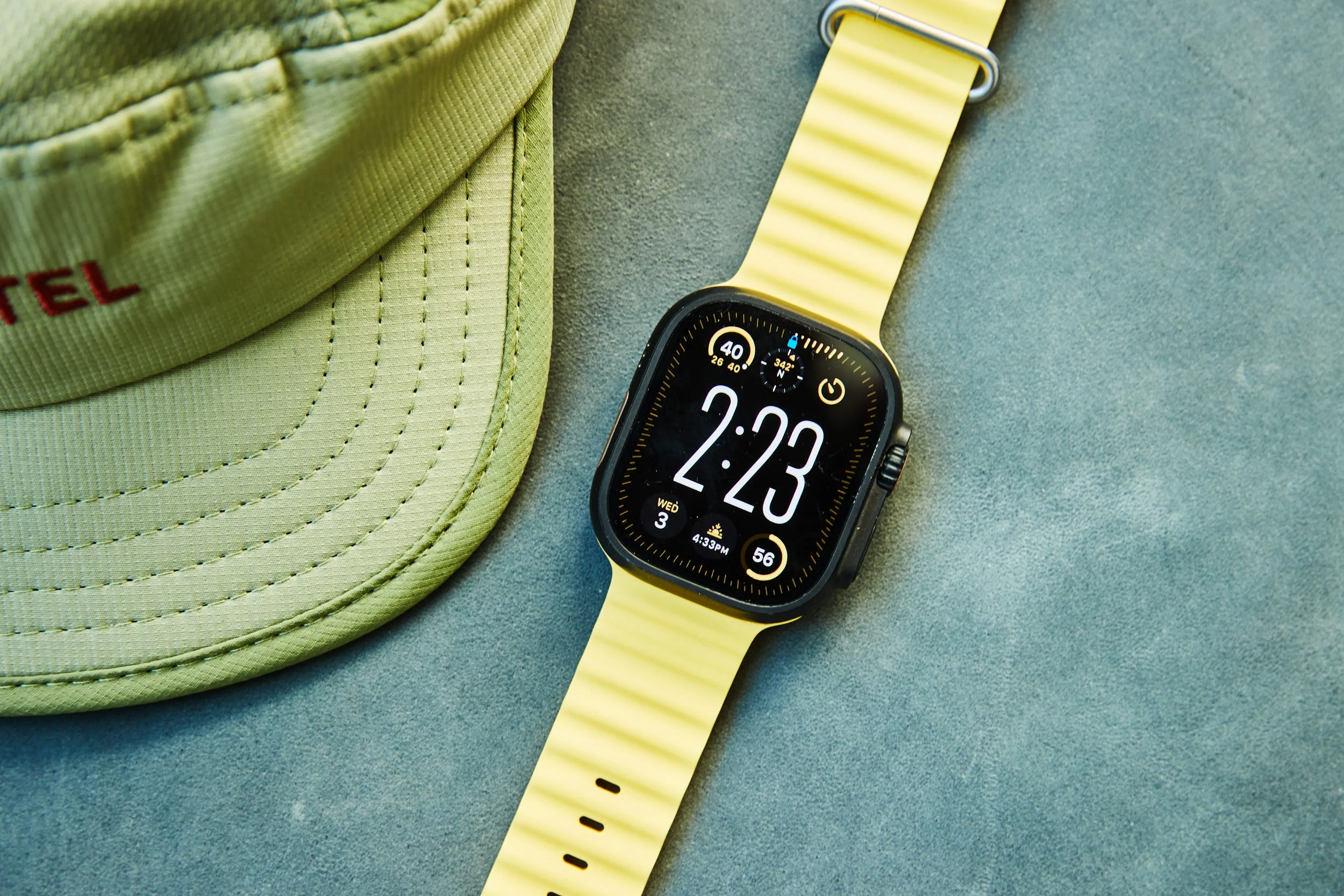 Wristwatch displaying time with a light yellow band next to a green cap Wristwatch displaying time with a light yellow band next to a green cap
